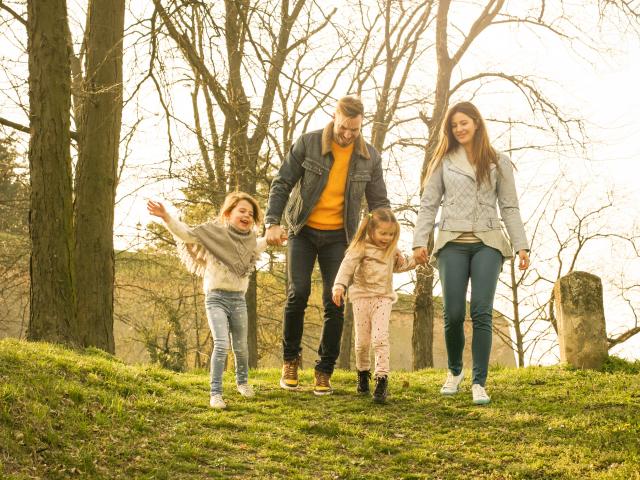 Happy parents playing with their daughters in the park. Space for copy.