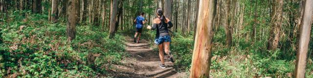 Young woman and man participating in a trail race through the forest