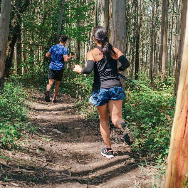 Young woman and man participating in a trail race through the forest