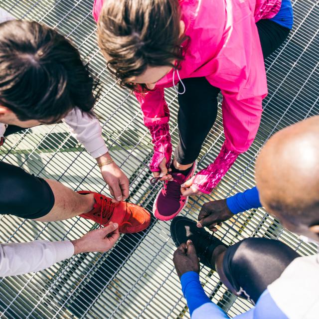 Multiethnic group of runners getting ready for a workout session - Athletes tying shoelaces and resting after a run outdoors