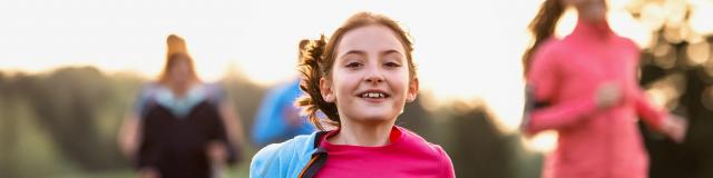 A portrait of small girl with large group of people running in nature.