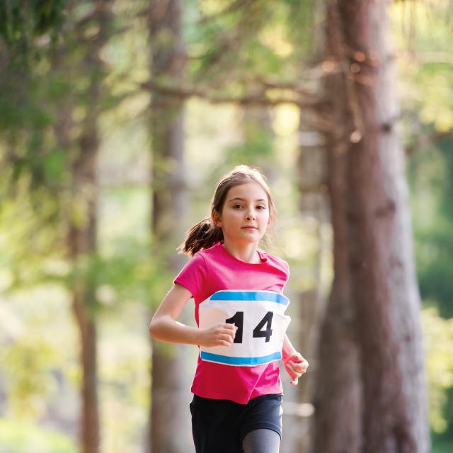 A front view of small child running a race competition in nature. Copy space.