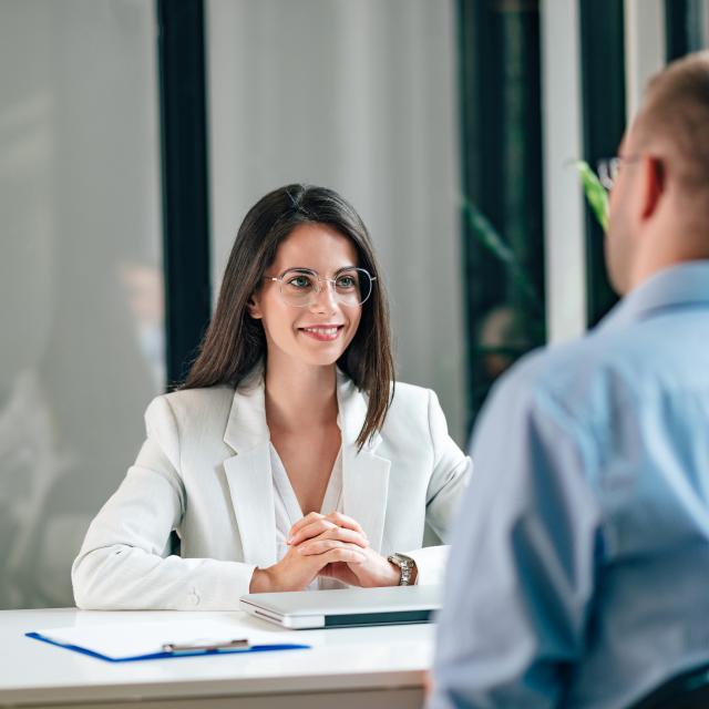 Smiling young corporate personnel manager talking to a male job applicant.