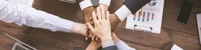 Corporate unity. Multiethnic business team stacking hands together on meeting, top view