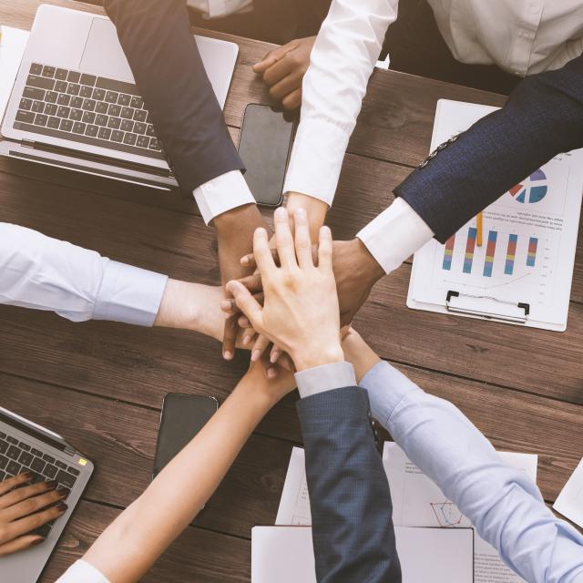 Corporate unity. Multiethnic business team stacking hands together on meeting, top view