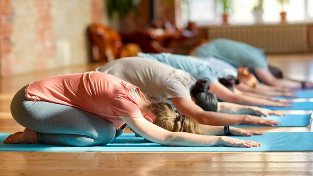 fitness, sport and healthy lifestyle concept - group of people with personal trainer doing yoga exercises on mats in gym or studio